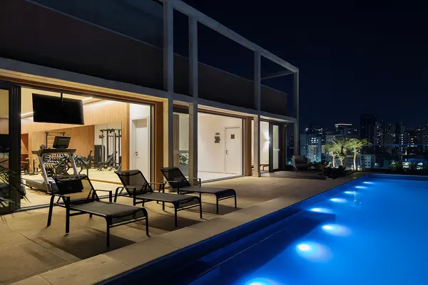Piscina com borda infinita do Hall Design à noite, iluminada, com a cidade ao fundo